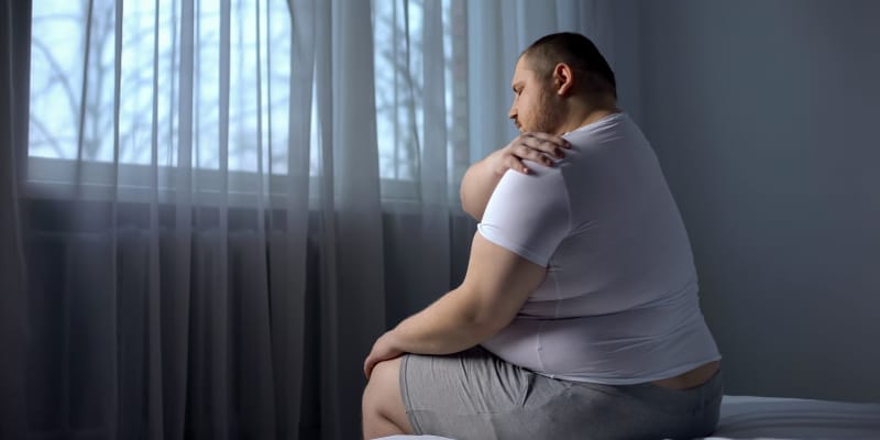 An obese man is dealing with an ache in his shoulder.