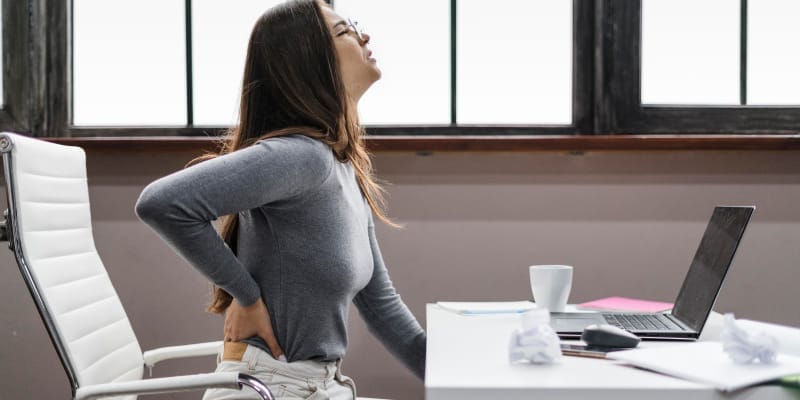 A woman has severe low back pain due to her sitting posture while working.
