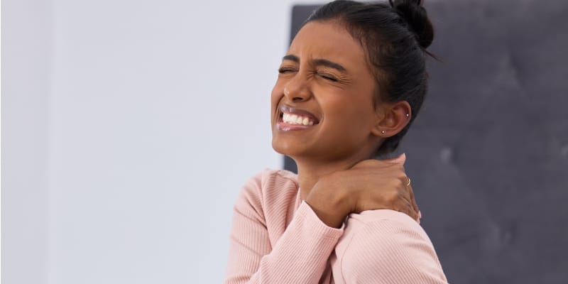 Stressed woman sitting, holding her back in pain, emphasizing the link between stress and orthopedic health.