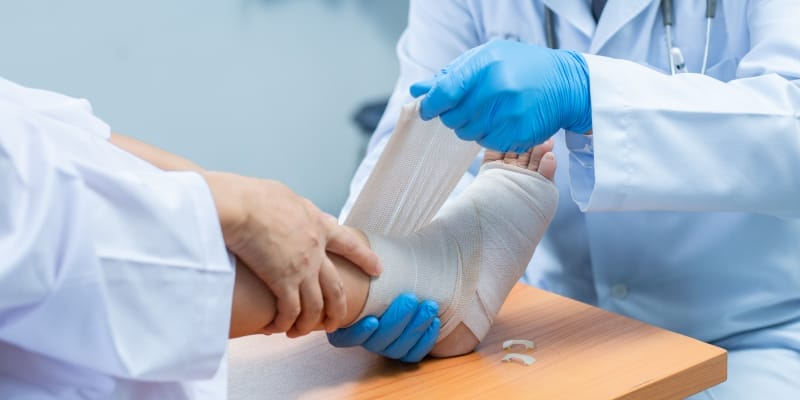 A doctor helping a patient with fracture in his leg.