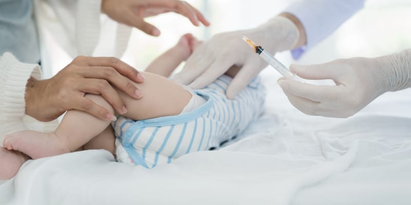 Newborn baby receiving routine vaccination from pediatrician during first newborn check-up at clinic to protect against early childhood diseases.