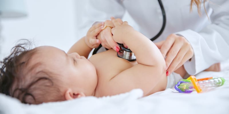 Paediatrician listening to infant&rsquo;s heartbeat with stethoscope during routine paediatric checkup, highlighting importance of early childhood healthcare.